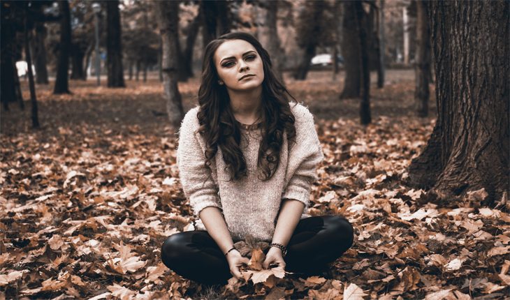 Woman struggling with bipolar disorder sitting in forest